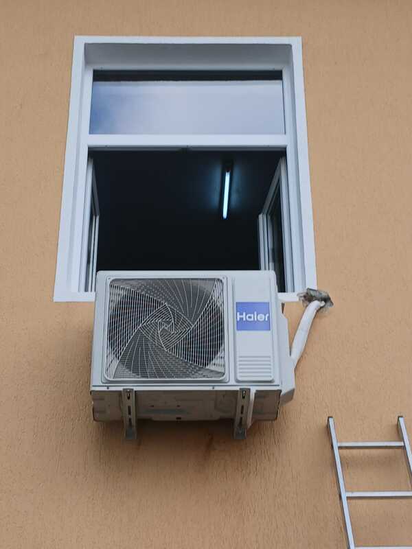 Instalare profesională AC Haier pe perete exterior sub geam.